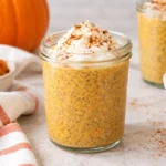 Pumpkin chia pudding in a glass jar topped with yogurt and pumpkin pie spice