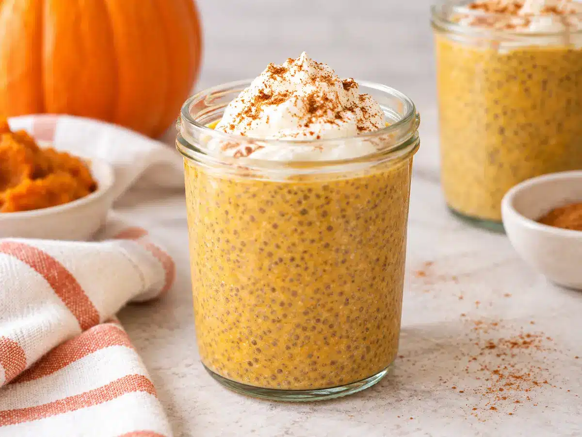 Pumpkin chia pudding in a glass jar topped with yogurt and pumpkin pie spice